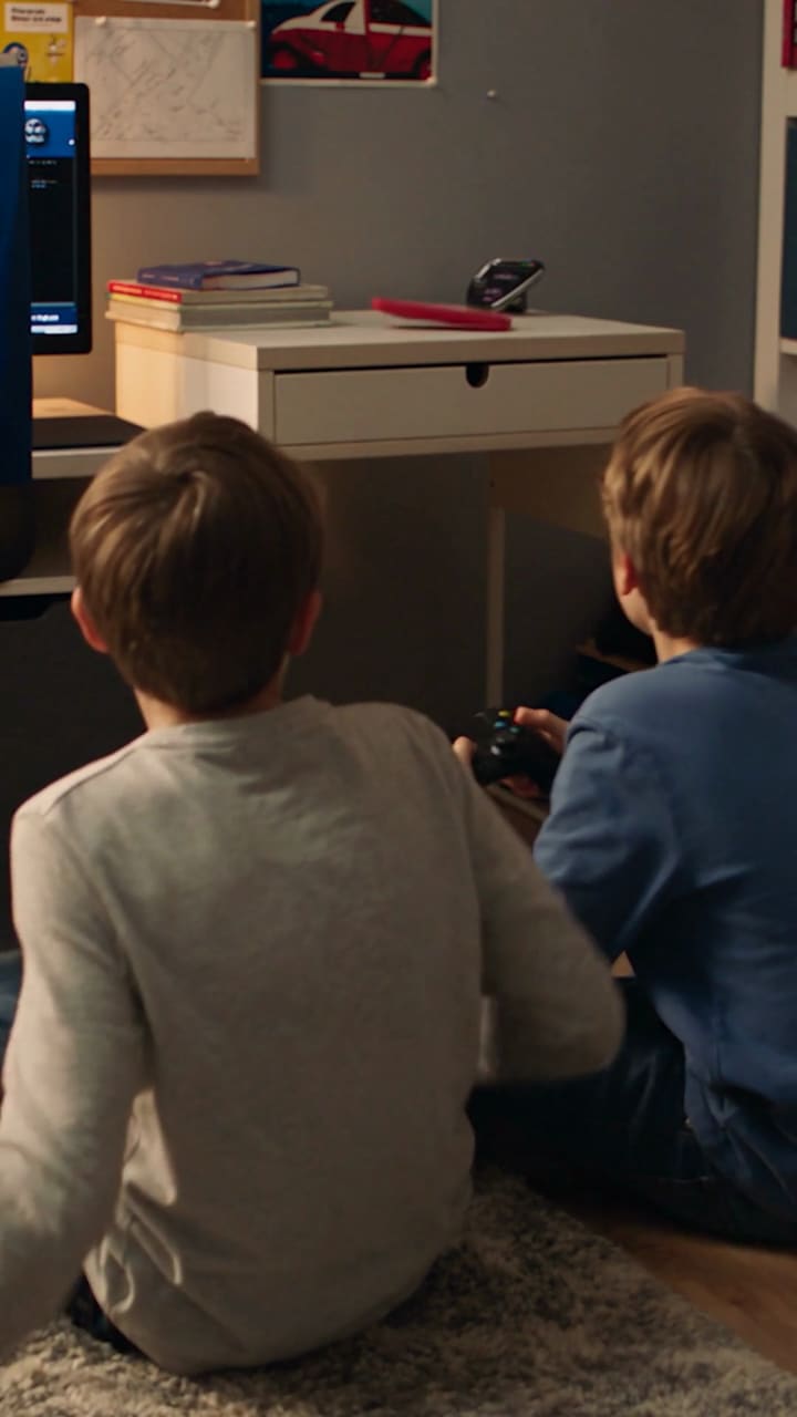 Zwei Jungen sitzen vor dem Fernseher und spielen mit Controllern.